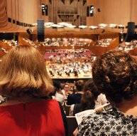 Blick von der hinteren Empore durch das Publikum auf ein klassisches Orchester